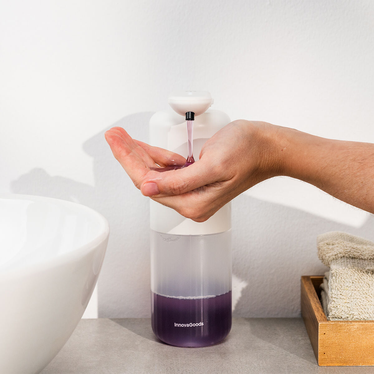 Distributeur Bitesap blanc et transparent distribuant du savon liquide dans une main près d’un lavabo